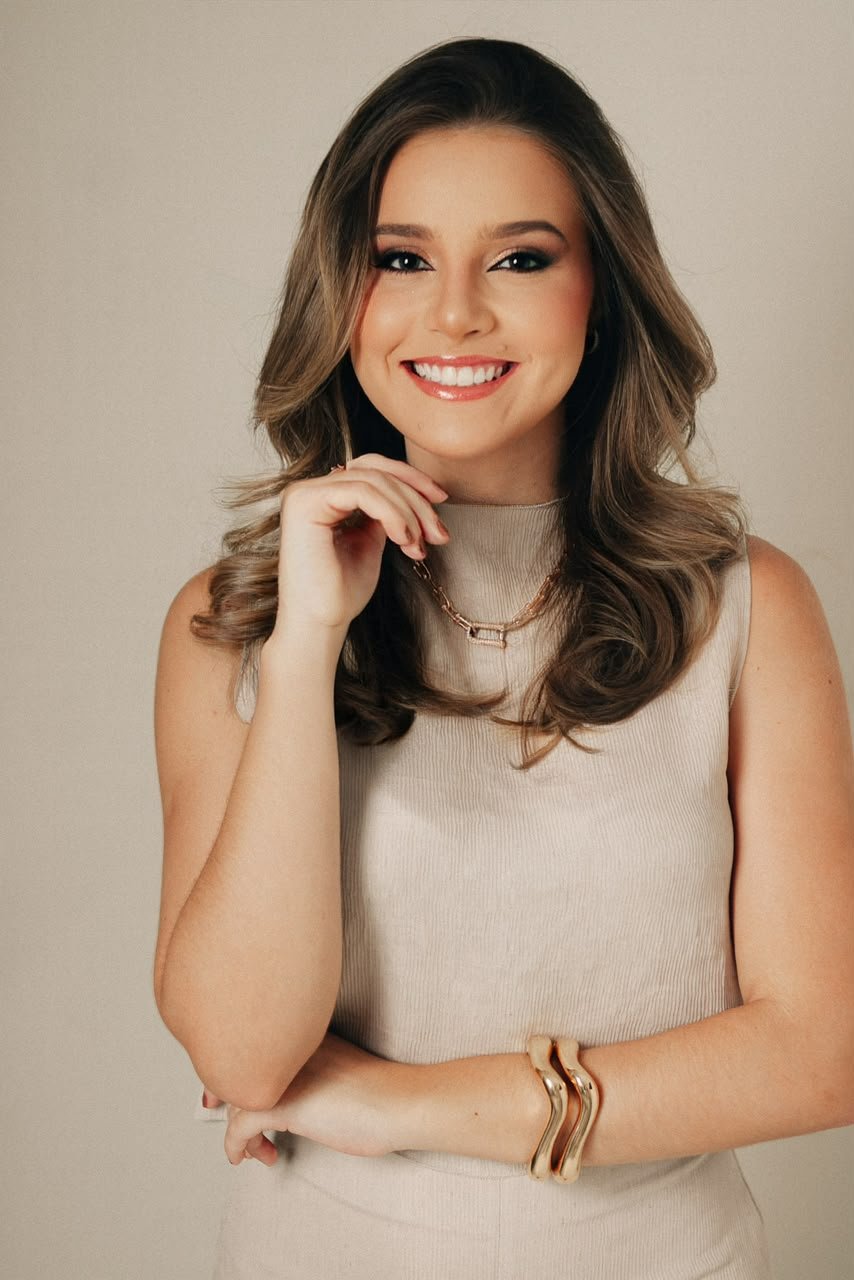 Dra. Gabriela Nasiasene sorrindo, com a mão apoiada no queixo